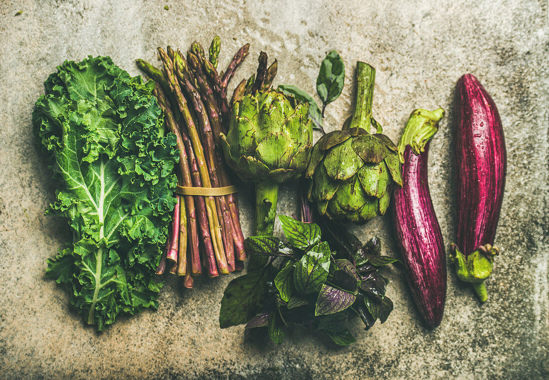 Green and purple fresh vegetables: Eggplans, green beans, kale, asparagus, artichoke, basil