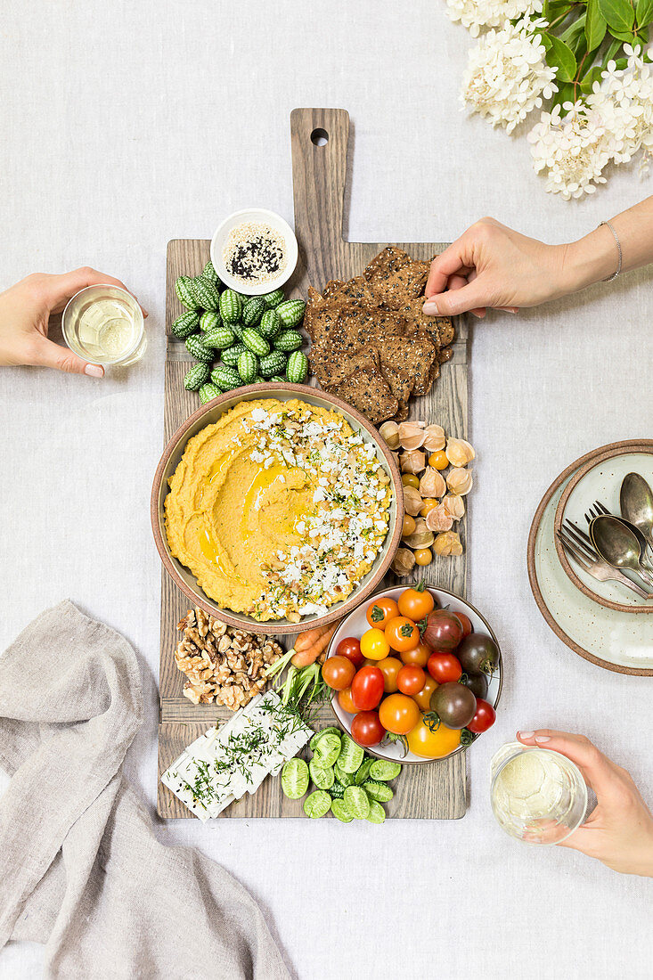 Hummus aus gerösteten Karotten mit Obst, Gemüse, Nüssen und Käse auf Servierplatte