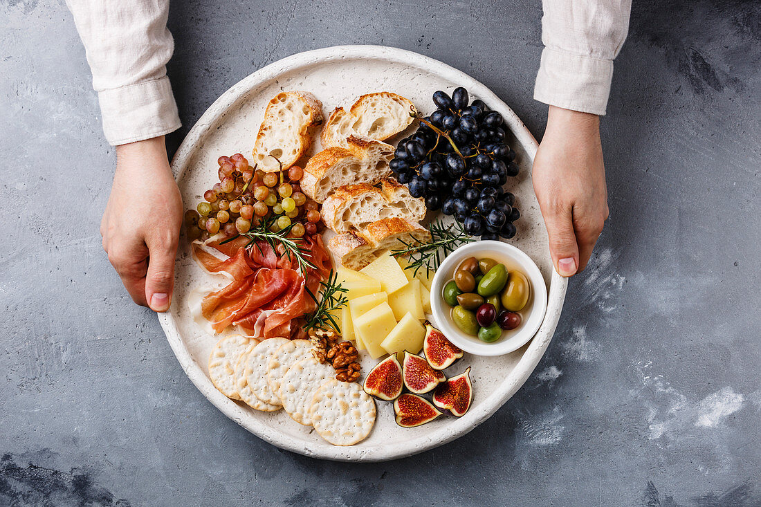 Italian snacks food with Ham, Olives, Cheese, Sun-dried tomatoes, Sausage and Bread in male hands