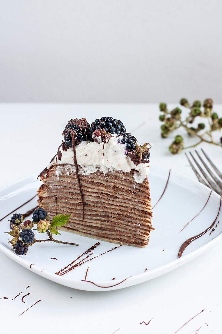 Ein Stück Crepetorte mit Schokolade und Brombeeren