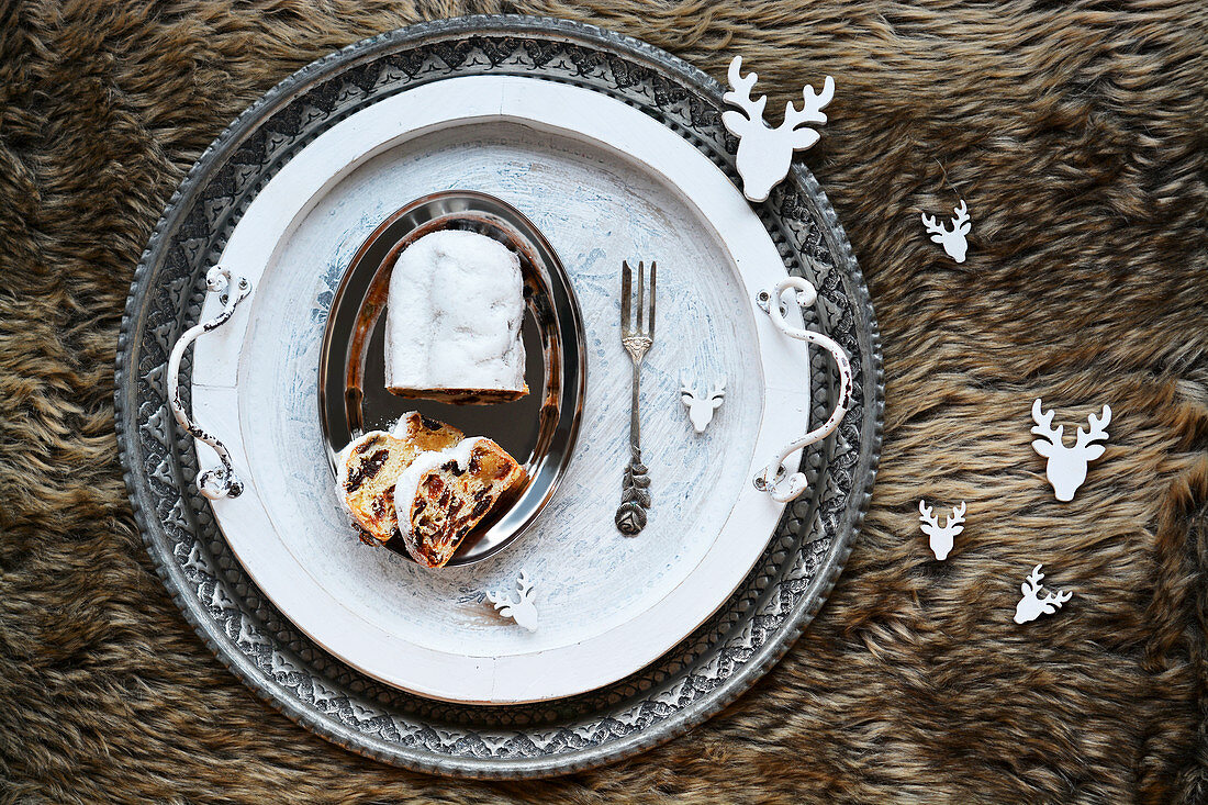 Sliced Christmas stollen on an artificial fur rug with deer decorations