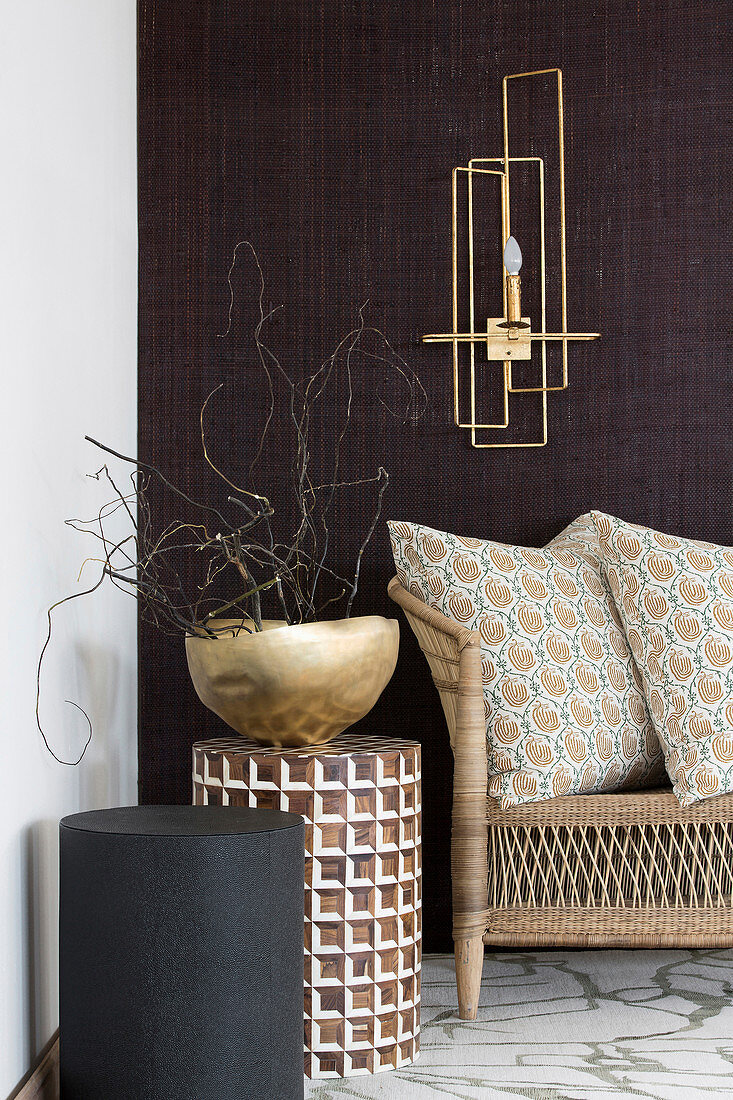 Round side tables and golden bowl below sconce lamp on dark wall