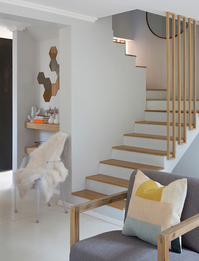 Sessel und Stuhl mit Schaffell vor der modernen Treppe mit Holzstufen