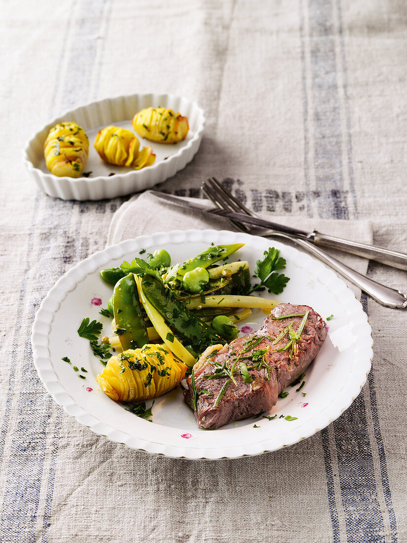Aromatically steamed beef steaks with beans, peas and potatoes