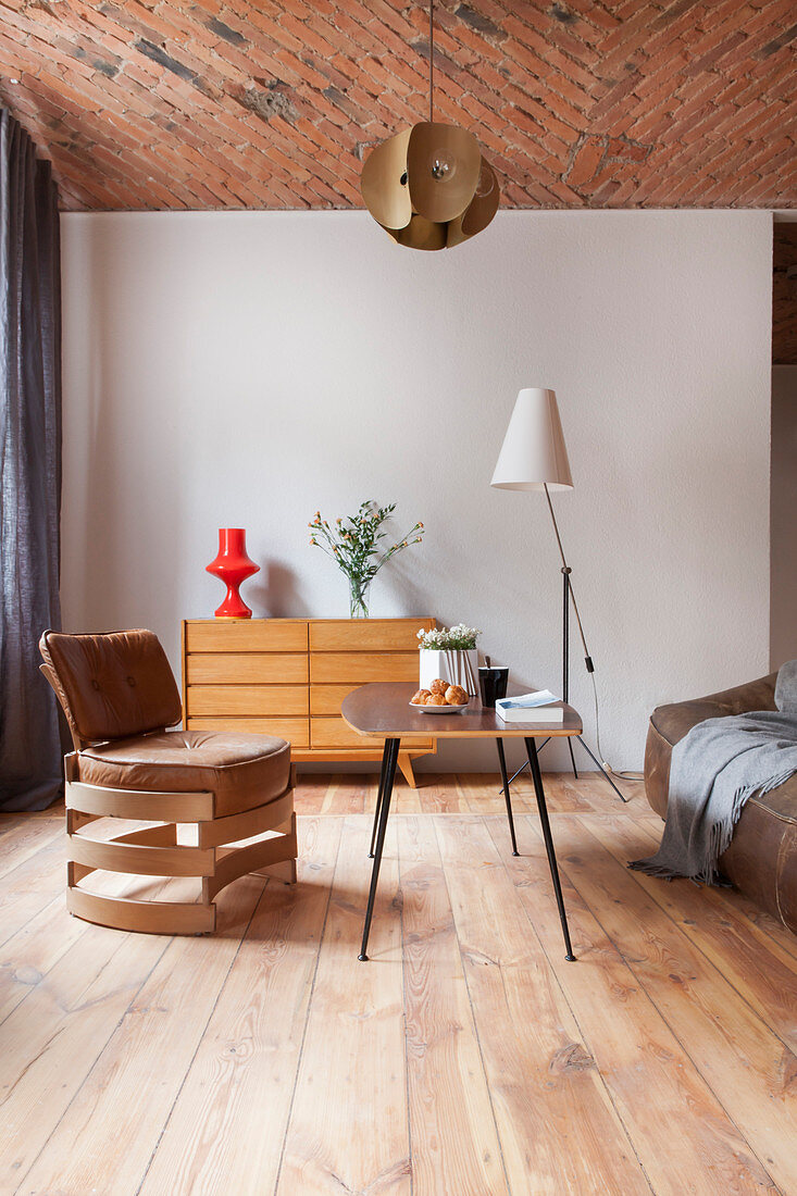 Designer-Lederstuhl, Coffeetable und Sideboard in offenem Wohnraum mit Ziegeldecke