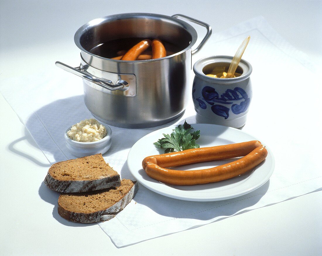 Frankfurters on a Plate and in a Pan; Mustard and Bread