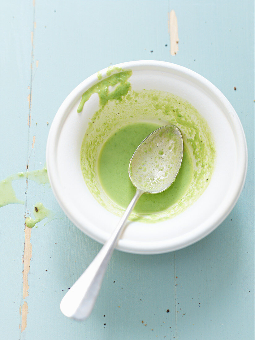 Remains of pea soup with bacon foam in a soup bowl