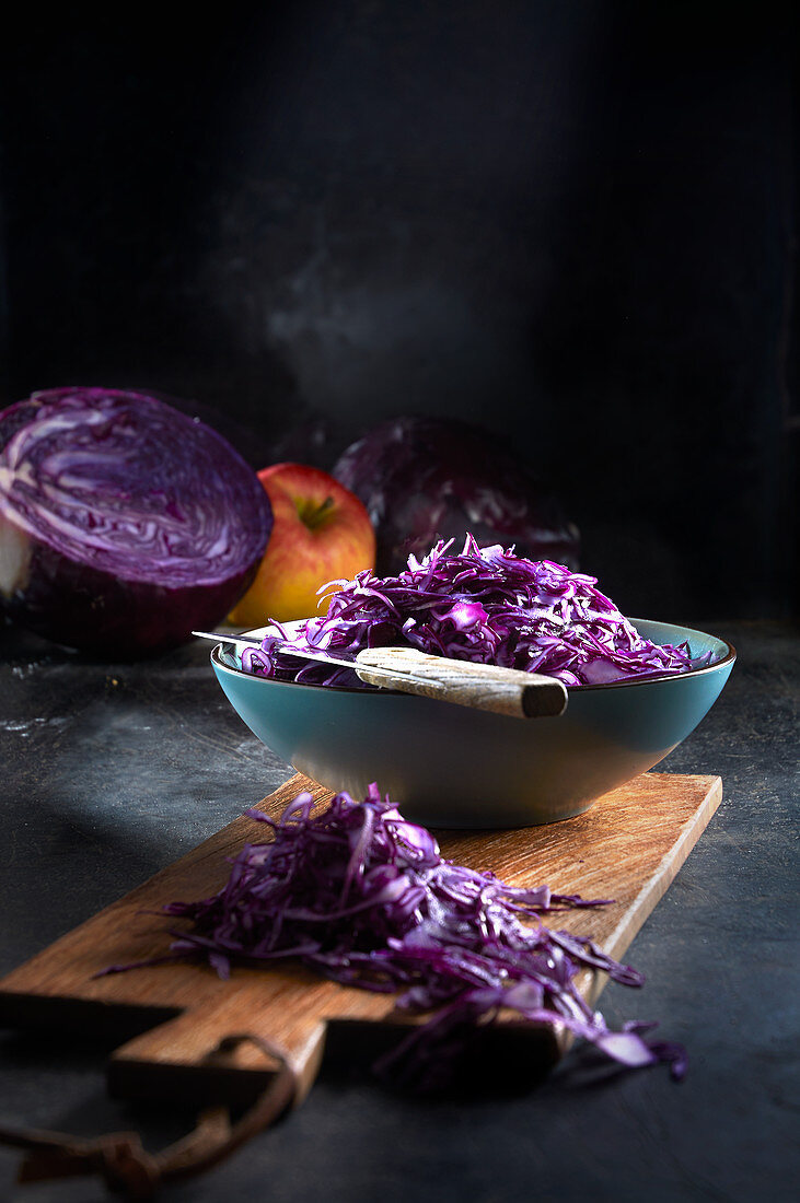 Sliced red cabbage in a bowl on a wooden board