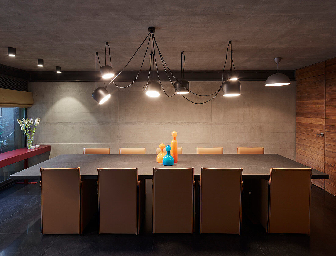 Designer lamp above long dining table in modern architect-designed house