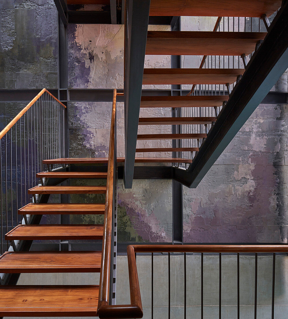 Open-plan, wood and steel staircase with multicoloured stairwell wall