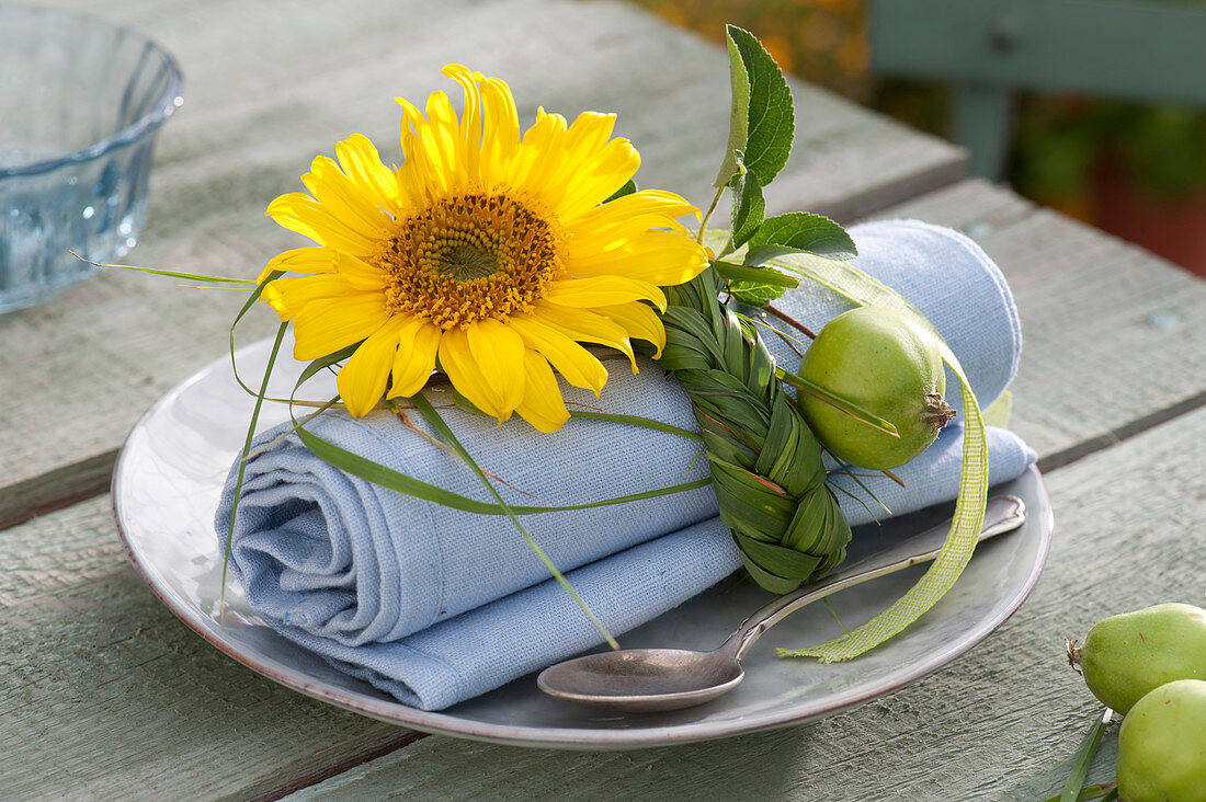 Braided grass plait as a napkin ring, decorated with Helianthus blossom