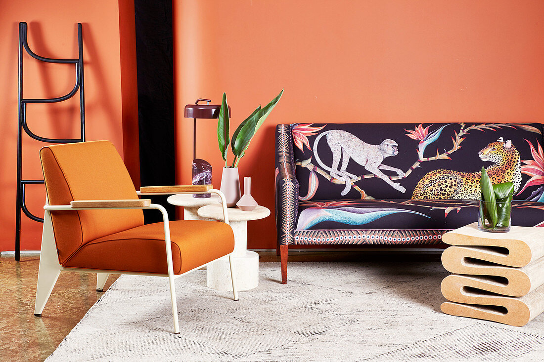 Designer-Sofa in Afrika-Look, Beistelltisch, Leiter, Armlehnstuhl und Couchtisch im Wohnzimmer mit orangefarbener Wand