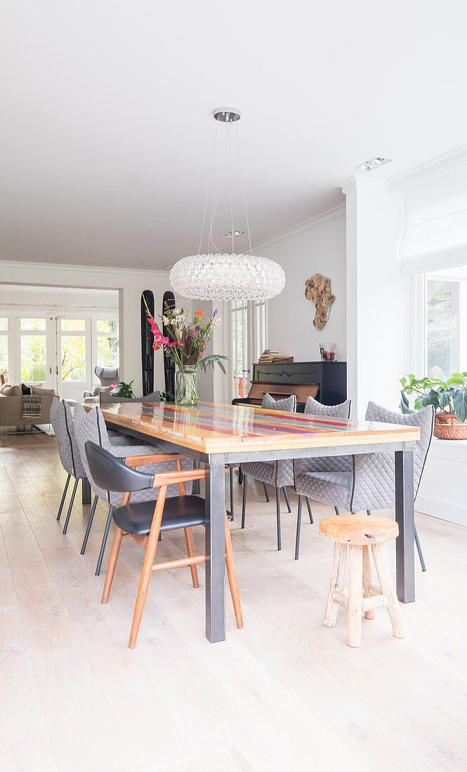 Long, colourful table and grey chairs in bright dining area