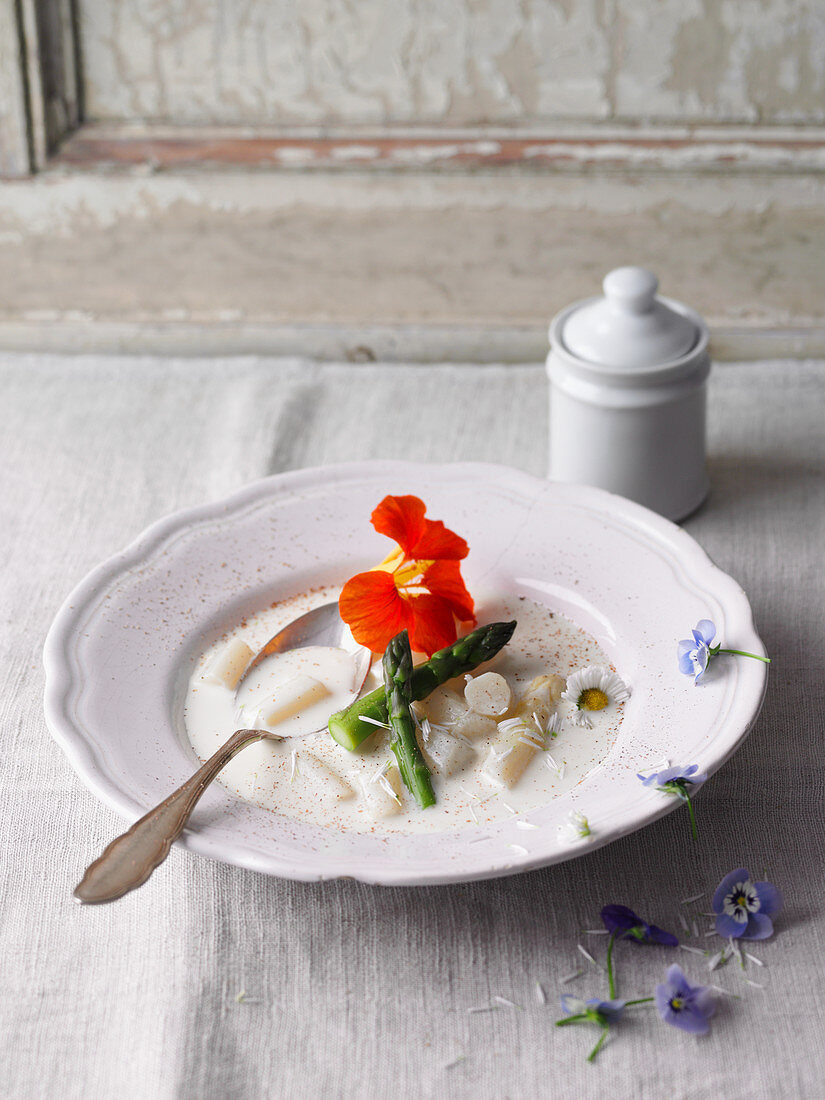 Cream of white asparagus soup with edible flowers