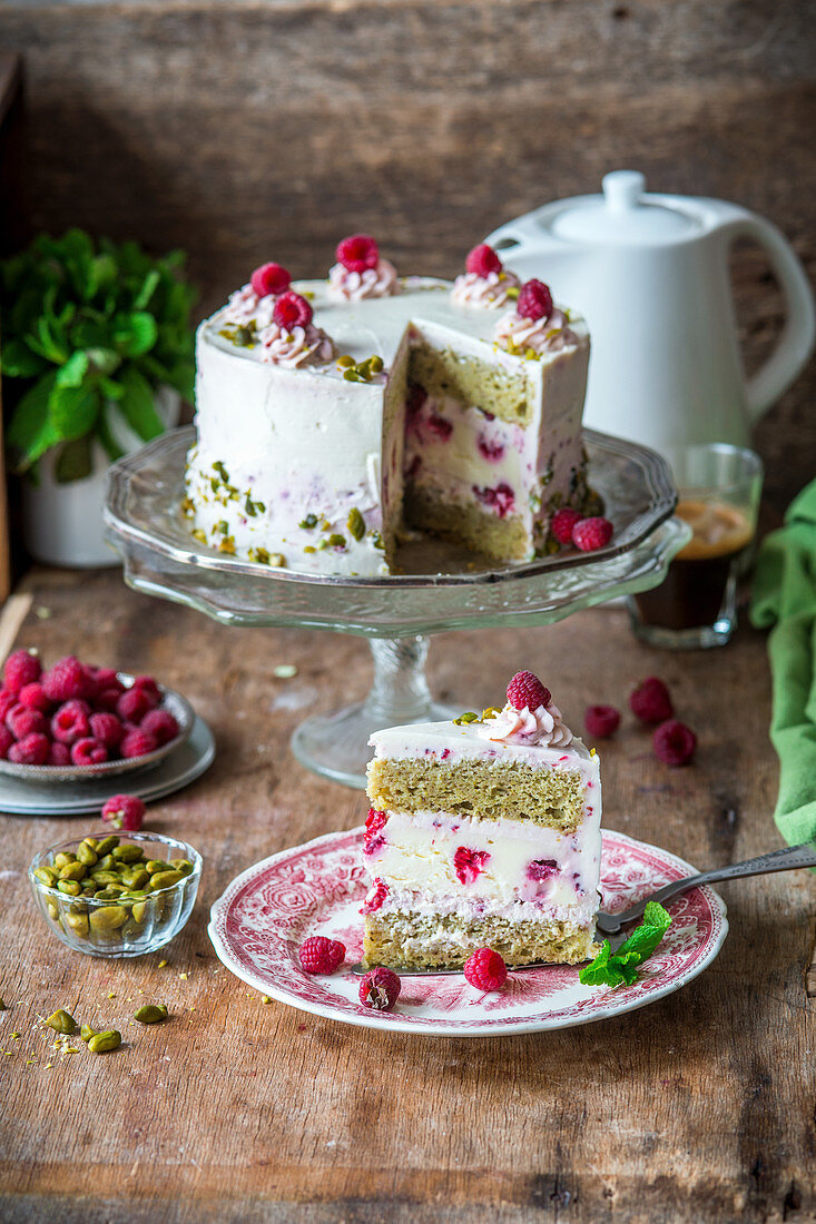 Cake with pistachio sponges, baked raspberry cheesecake layer and raspberry cream cheese