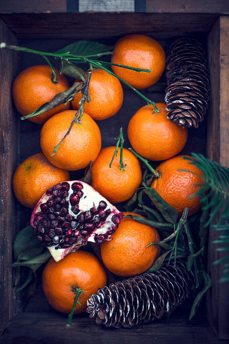 Mandarinen und Granatapfel in Holzkiste