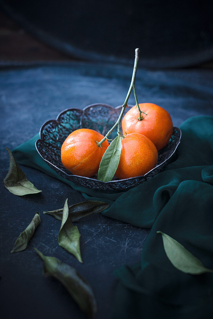 Frische Mandarinen mit Blattgrün im Drahtkorb
