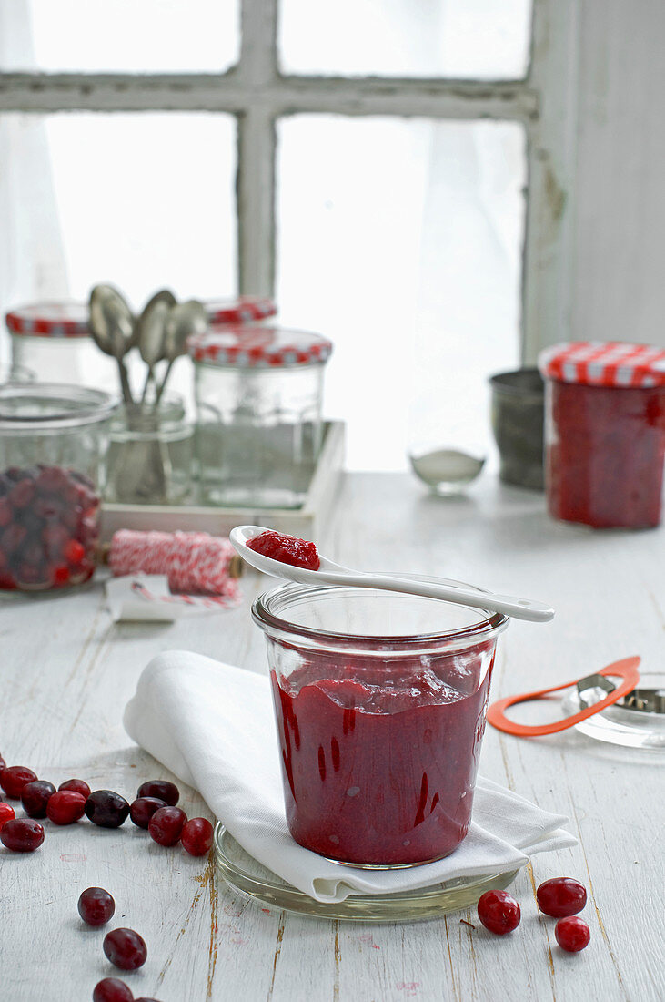 Cornelian cherry jam in a storage jar with a spoon