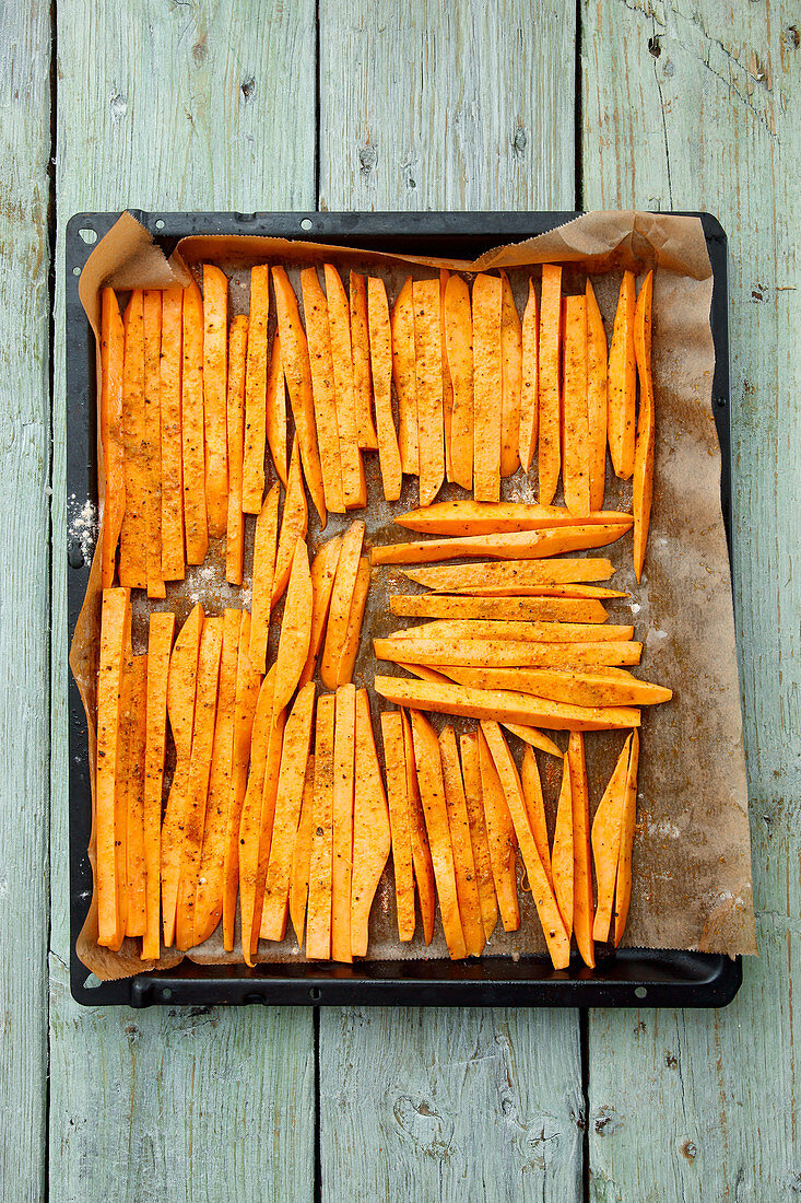 Sweet potatoes, peeled and sliced, on a baking tray
