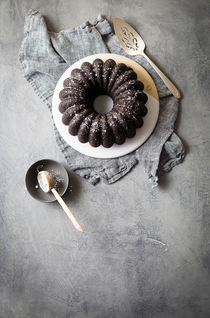 Dunkler Schokoladen-Kranzkuchen auf grauem Untergrund (Aufsicht)
