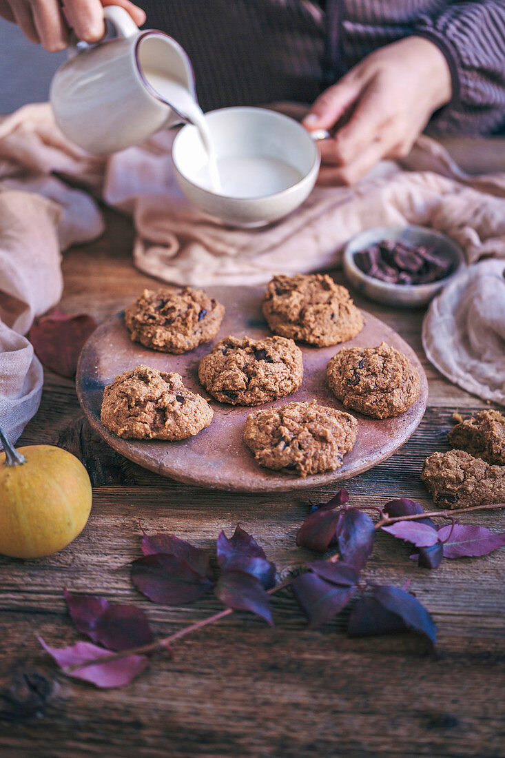 Woman eating pumpkin chocolate chip cookies with a cup of milk