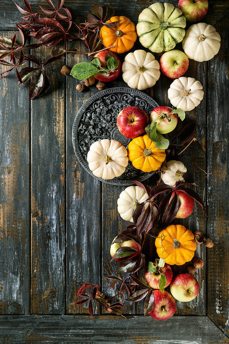 Autumn holiday table decoration setting with decorative pumpkins, apples, red leaves over wooden table