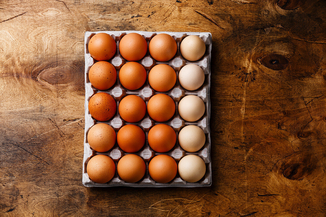 Fresh brown and speckled chicken Eggs in eco cardboard paper tray container on wooden background