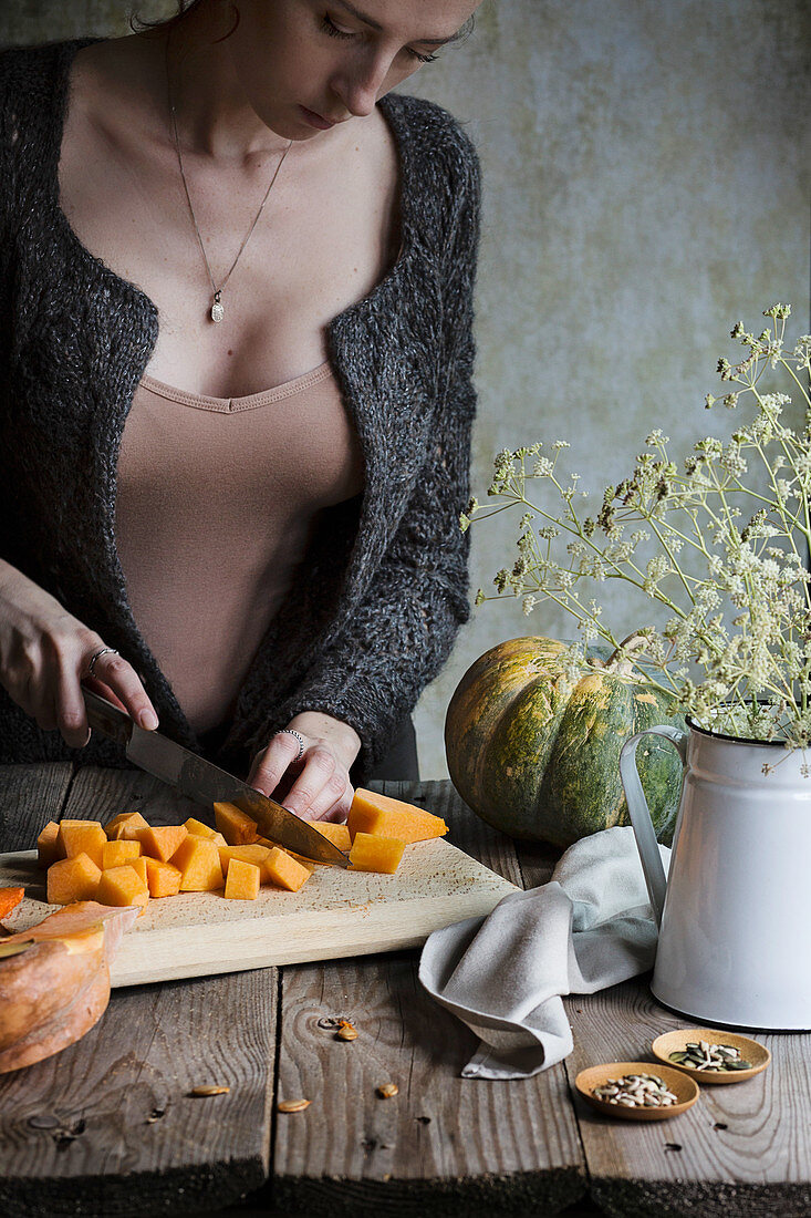 A woman chopping pumpkins on wooden rustic table