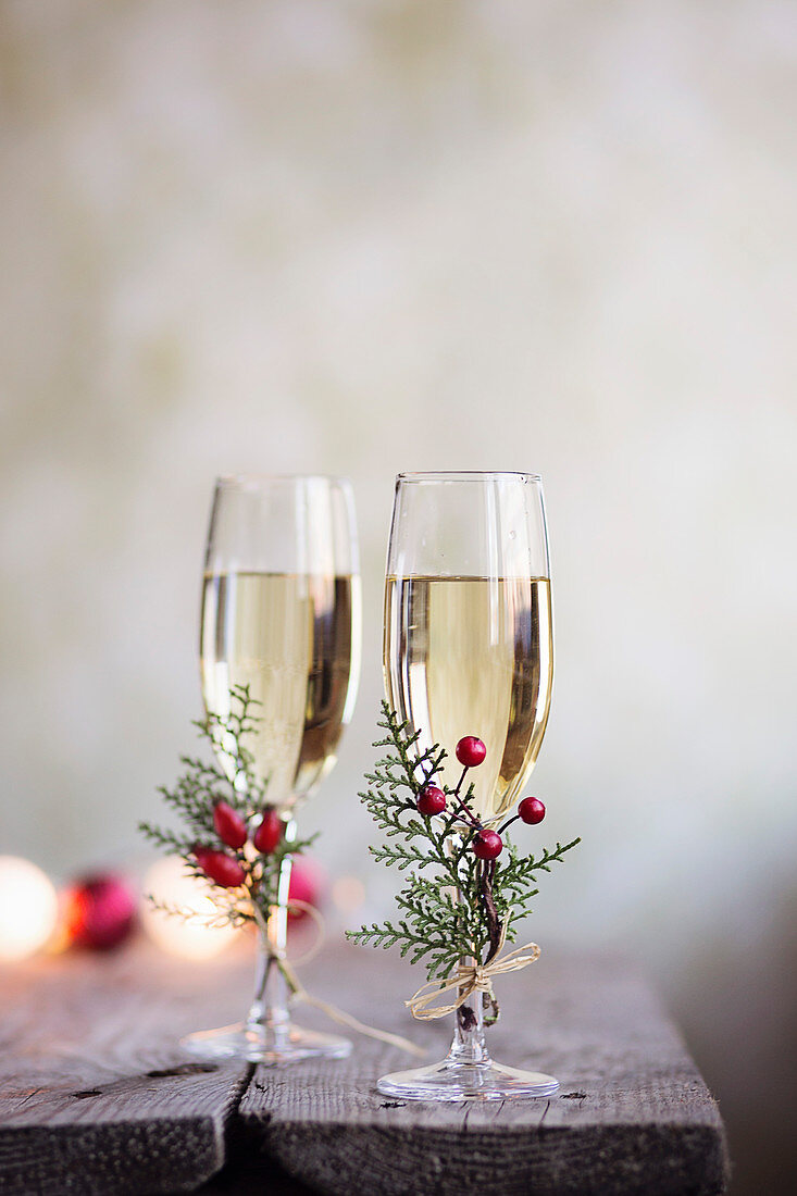 Zwei Champagnergläser weihnachtlich dekoriert mit Beerenzweigen