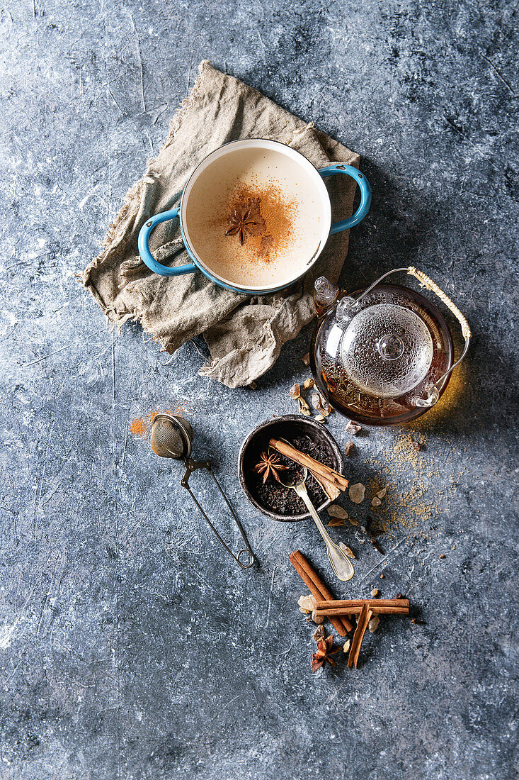 Vintage blue pot of traditional indian masala chai tea with ingredients above