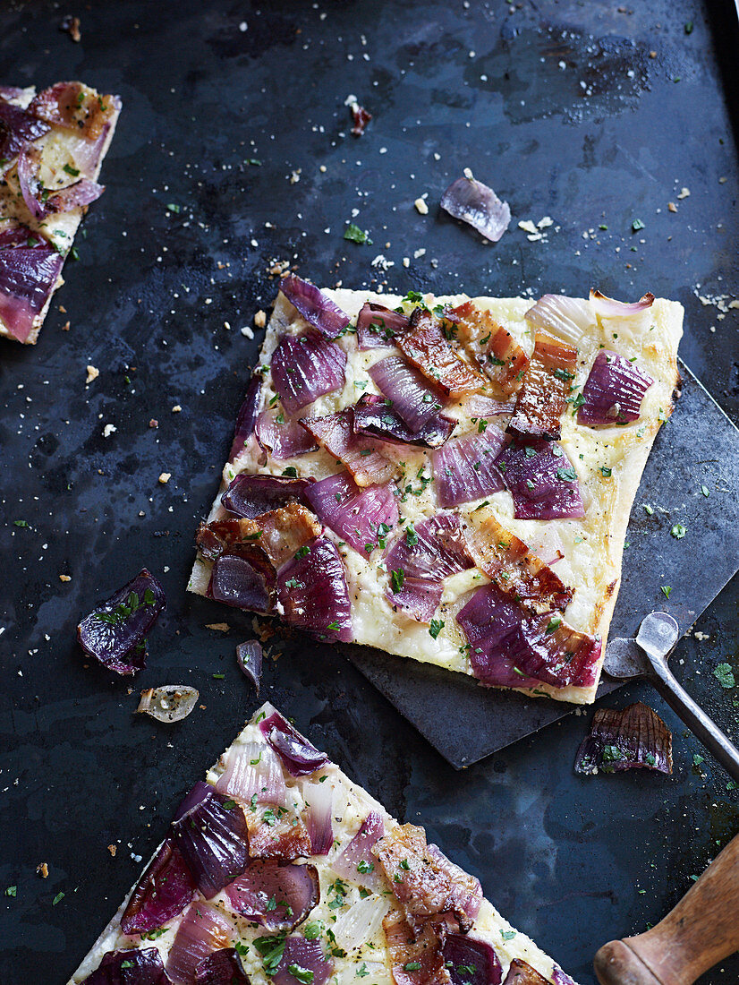 Tarte flambée with red onions on a baking tray