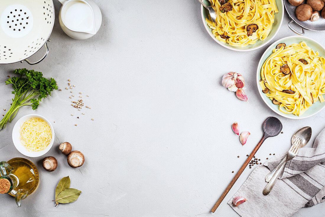 Tagliatelle mit Pilzcremesauce daneben Zutaten (Aufsicht)