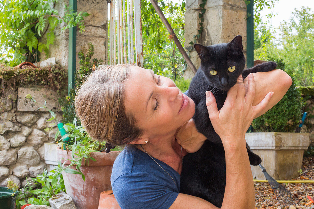 Woman holding a black cat in her arms