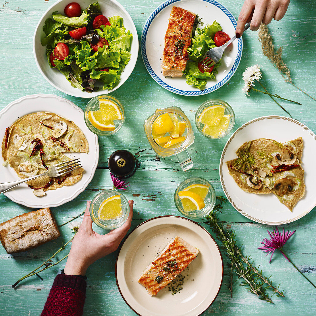 A table laid for lunch with salmon, pancakes and a mixed leaf salad