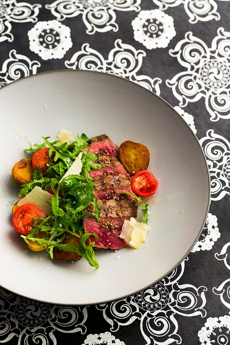 Tagliata with potatoes, parmesan cheese, pepper, salt, rocket and tomatoes
