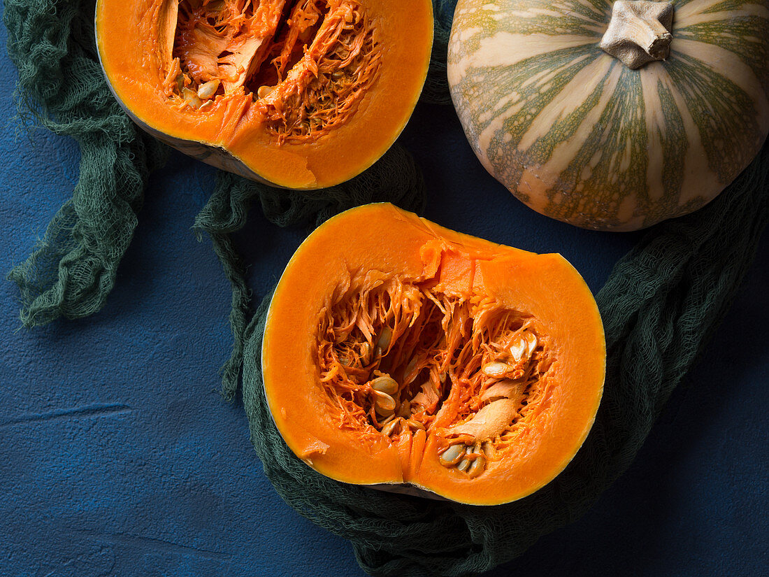 Raw small pumpkin cut in two parts on blue background