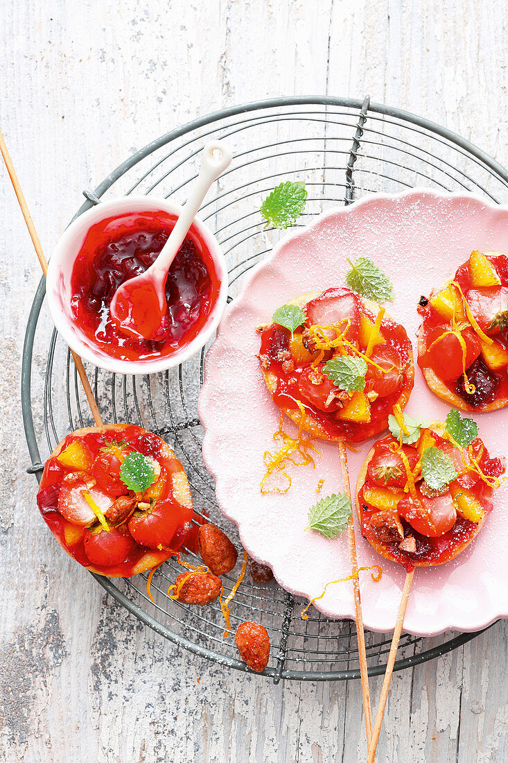 Grilled sweet mini pizzas on sticks topped with strawberries and almonds