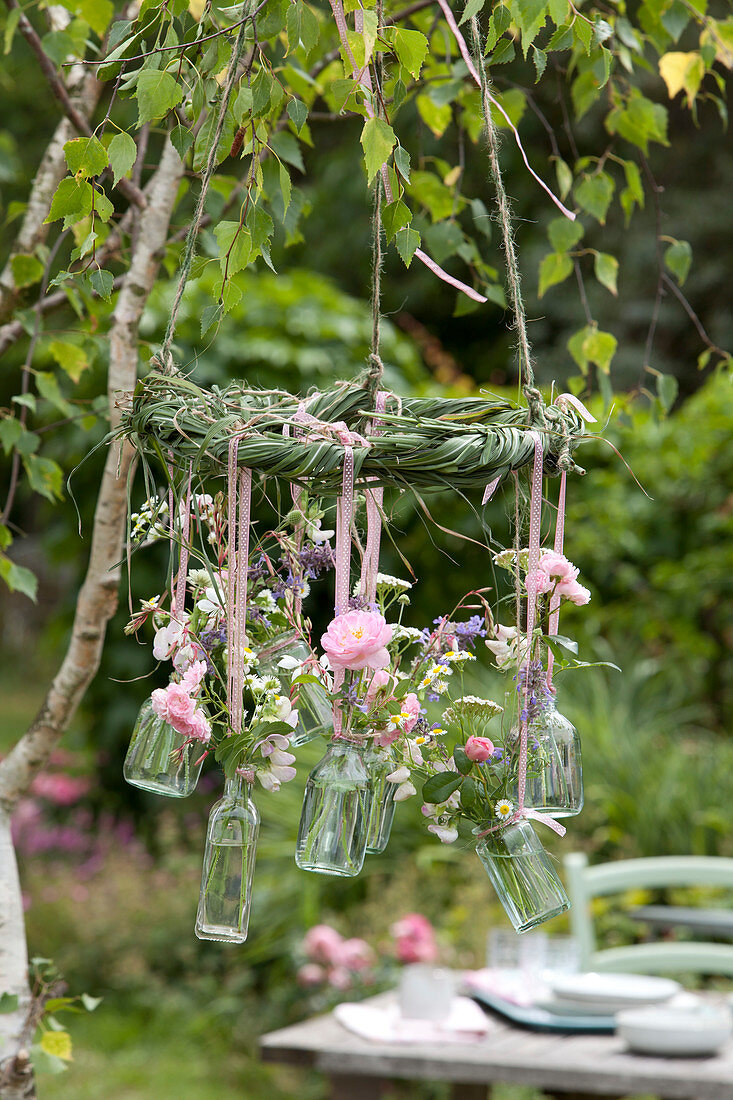 Small bouquets in hanging bottles on grass wreath