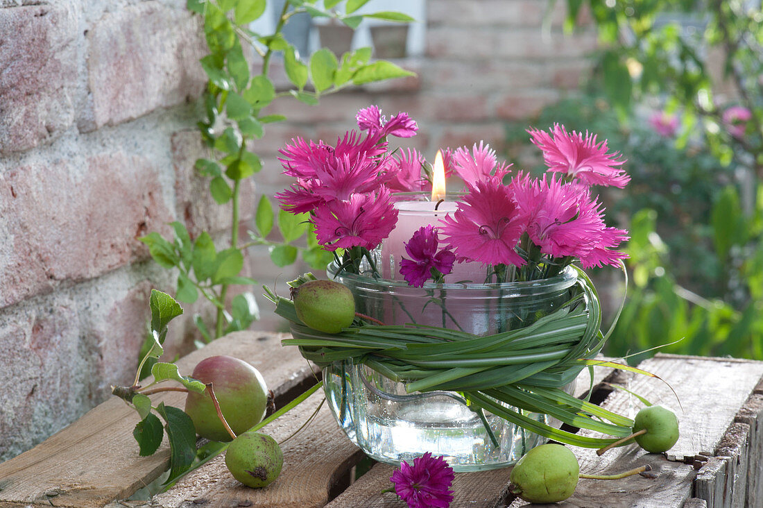Glass with candle in mason jar placed as a lantern, flowers of Dianthus