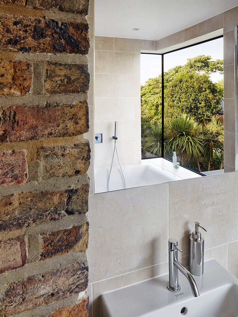 Modern bay window reflected in mirror in bathroom with brick wall