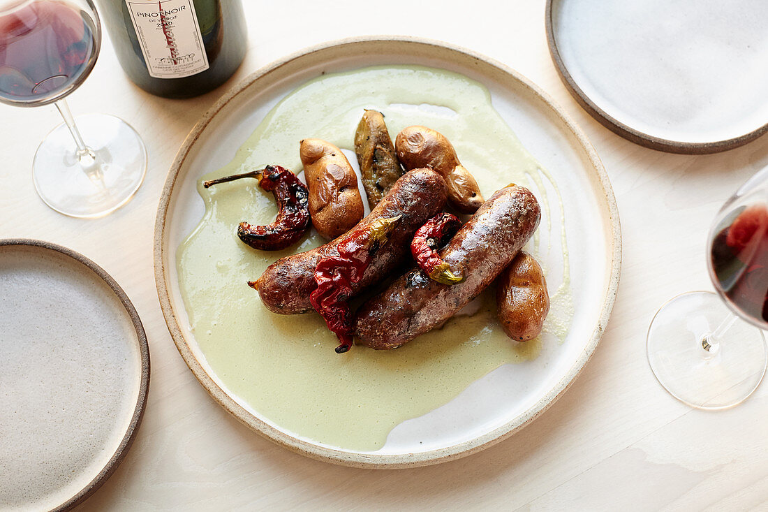A plate of sausages with potatoes and chile peppers
