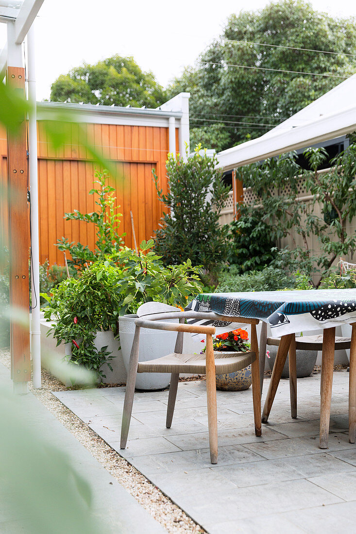 Holzstühle am Tisch mit Wachstuchtischdecke im Garten