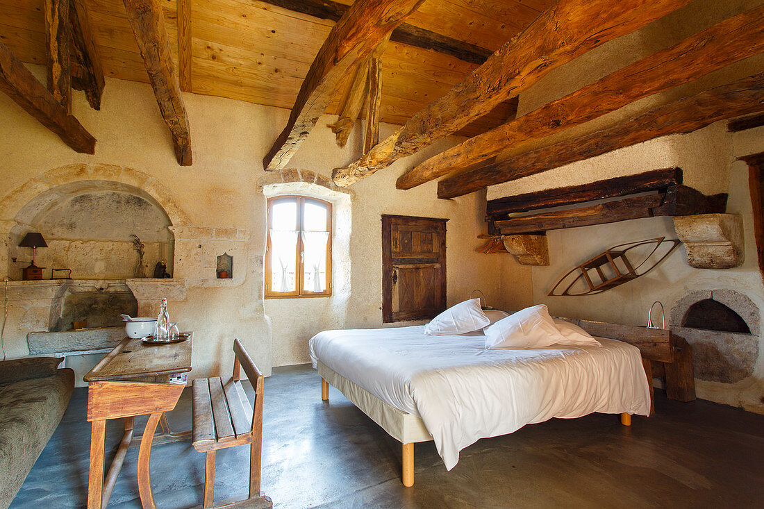 Old school desk and double bed in rustic bedroom