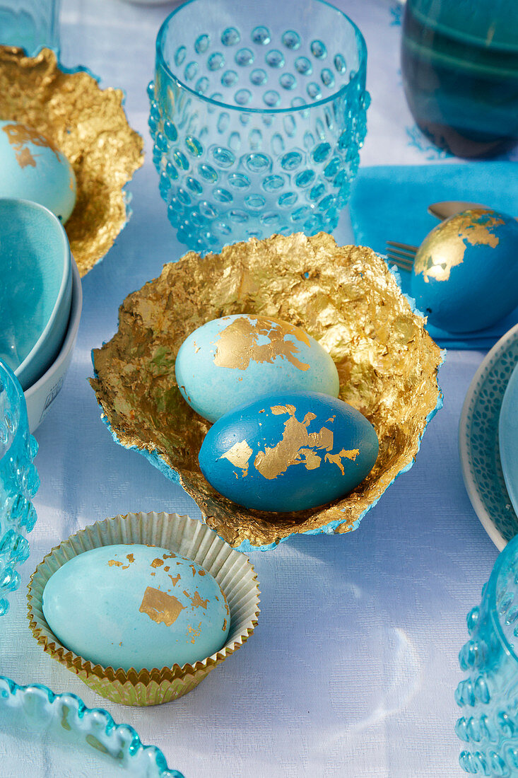 Ostereier und selbstgebastelte Pappmache-Schalen in Blau und Gold