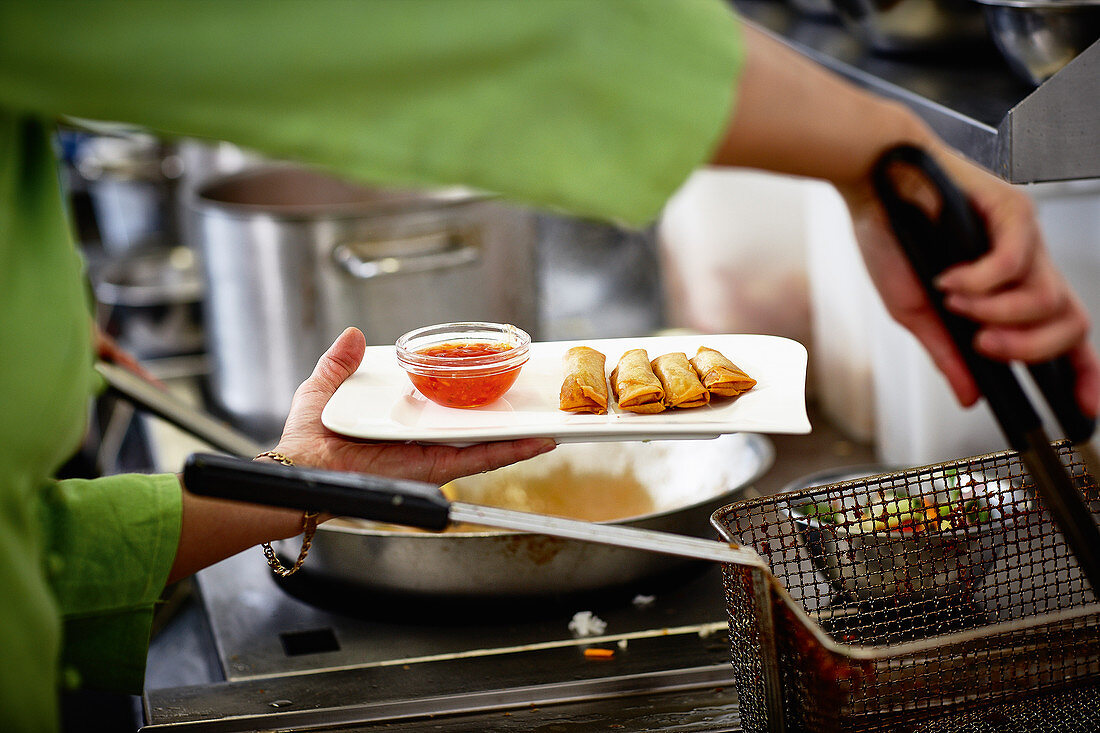 Mini-Frühlingsrollen aus Friteuse nehmen, mit süß-saurer Sauce anrichten