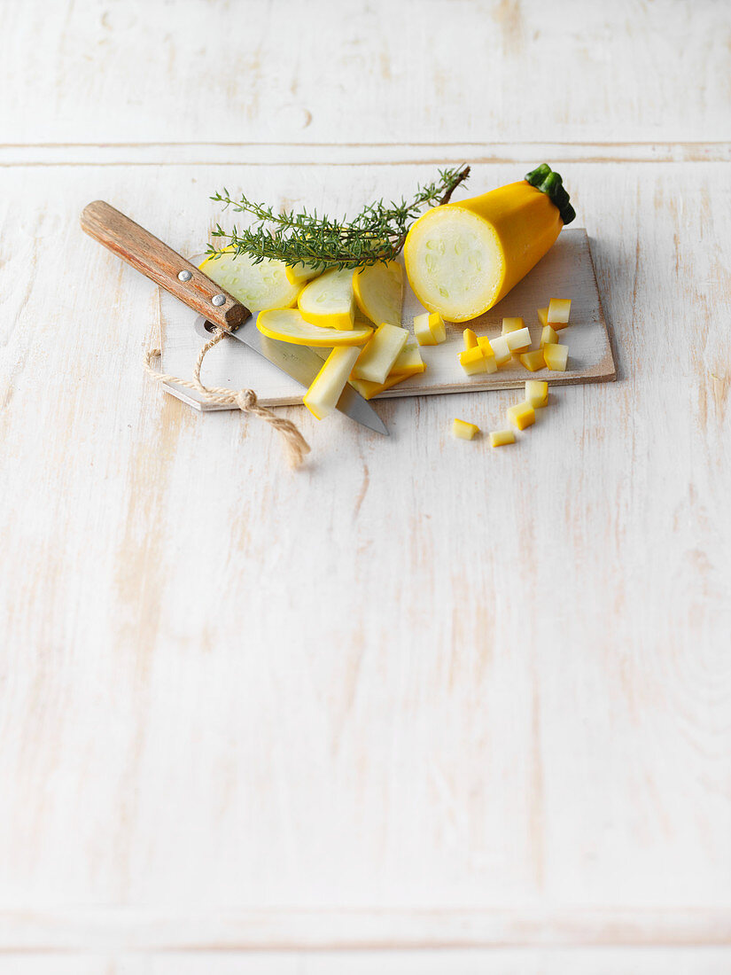 Sliced yellow courgette on a board with rosemary