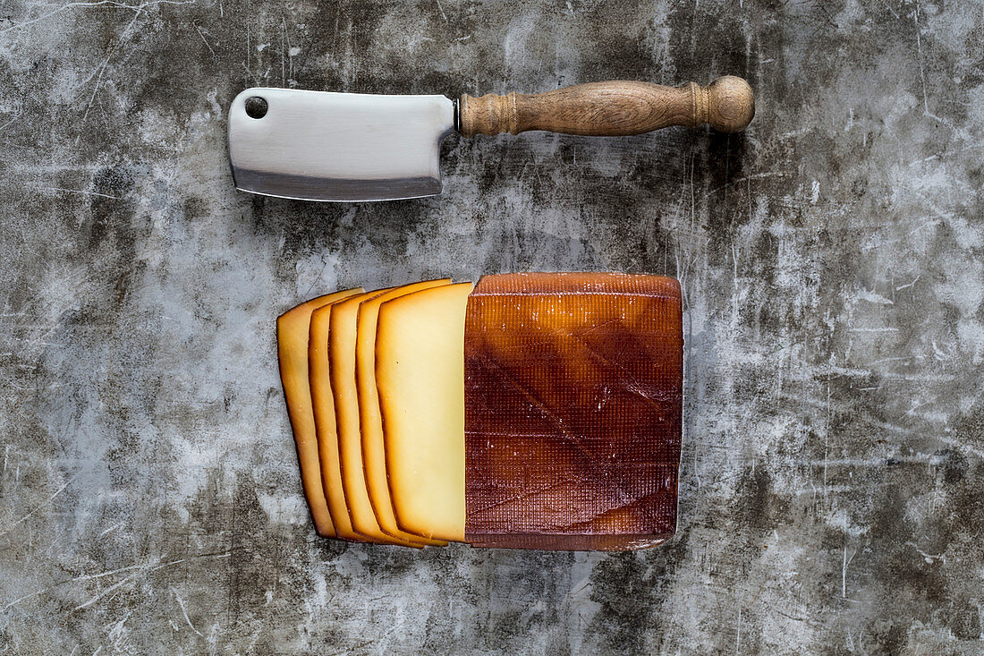 Geräucherter Käse, geschnitten auf grauem Metalluntergrund