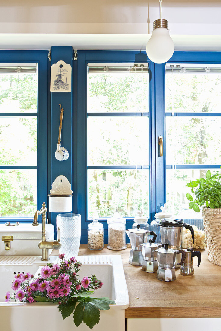 Landhausküche mit blauen Fenstern, Spülbecken und Espressokannen
