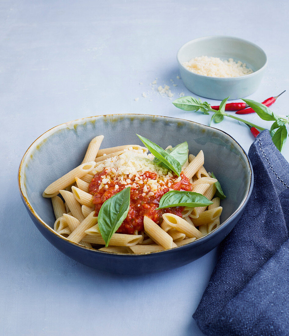 Wholemeal penne pasta with a tomato and courgette sauce and basil