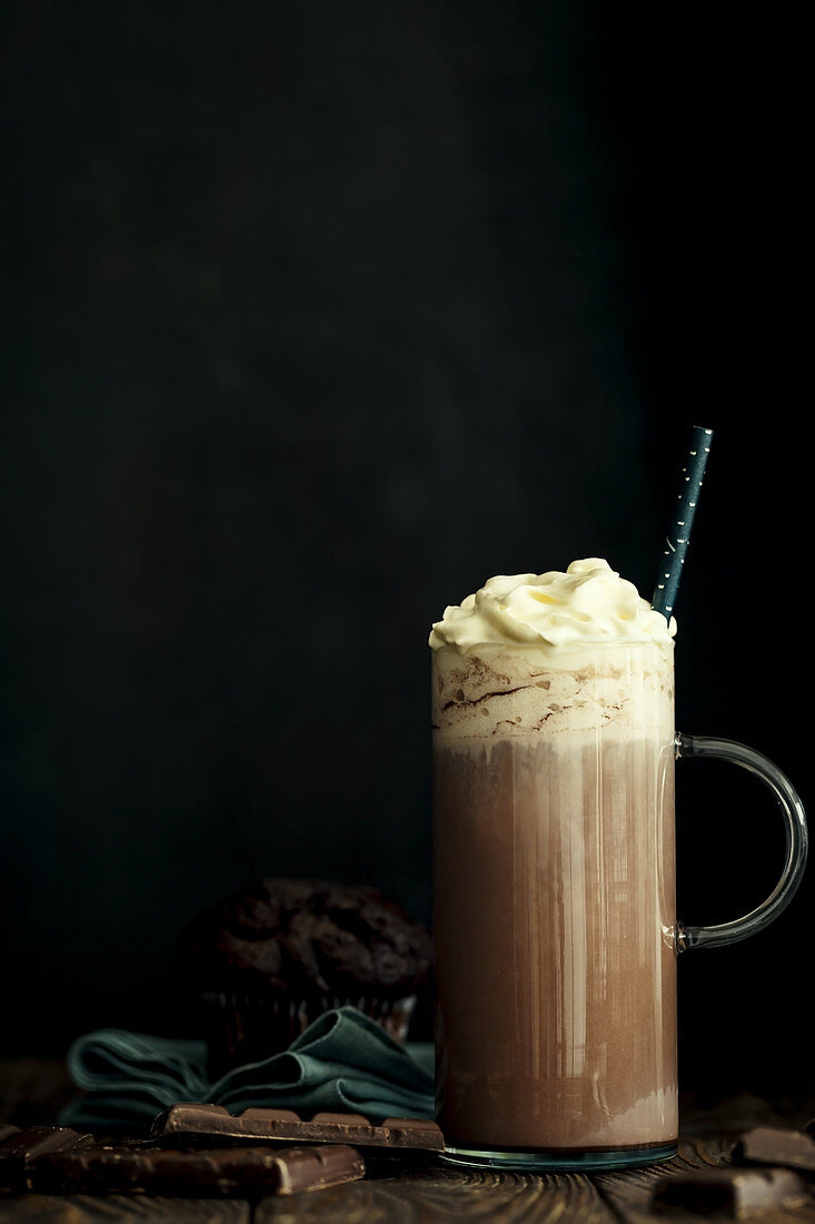 Hot chocolate with whipped cream in a jar witha handle against a black background